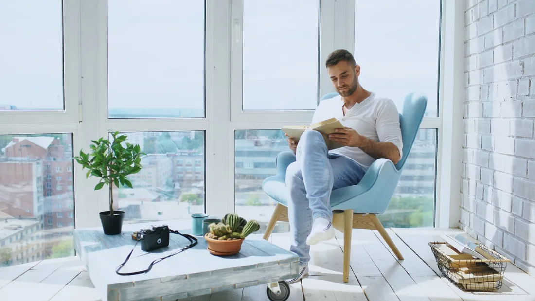 Person reading in a bright modern apartment with large windows and city view. Photo by Vitaly Gariev on Pexels