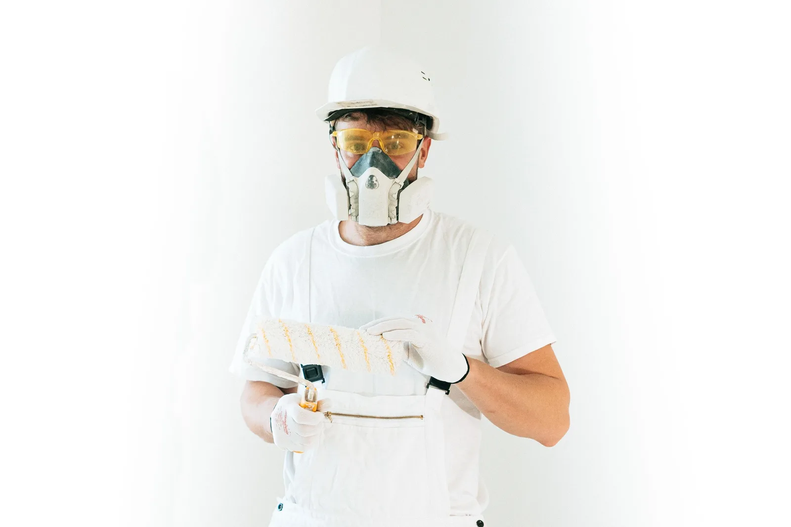A professional painter wearing safety gear holding a paint roller, ready for work. Photo by AI25.Studio  Studio on Pexels