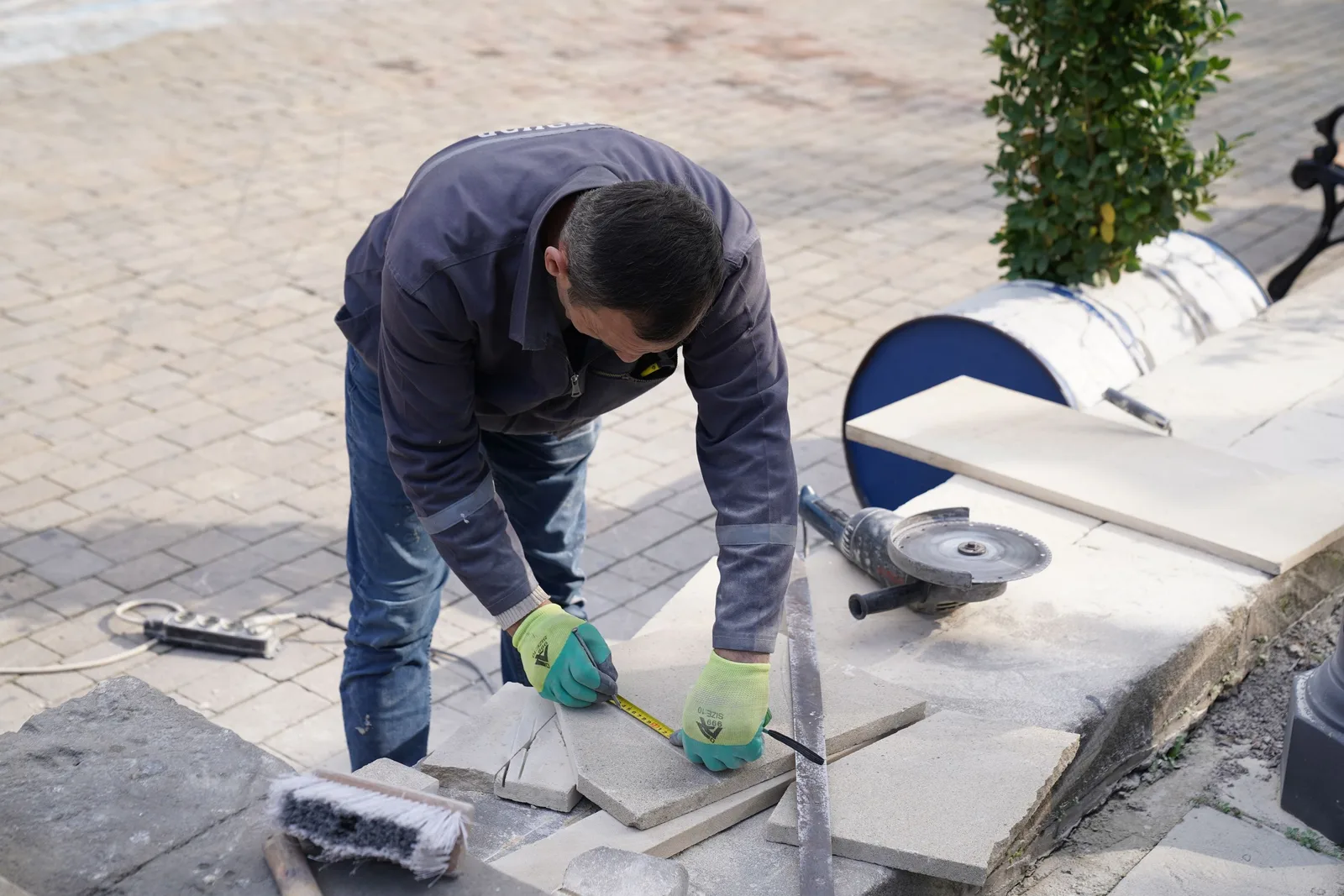 Paver cutting and laying stone slabs on a patio with a grinder. Photo by Tahir Xəlfəquliyev on Pexels