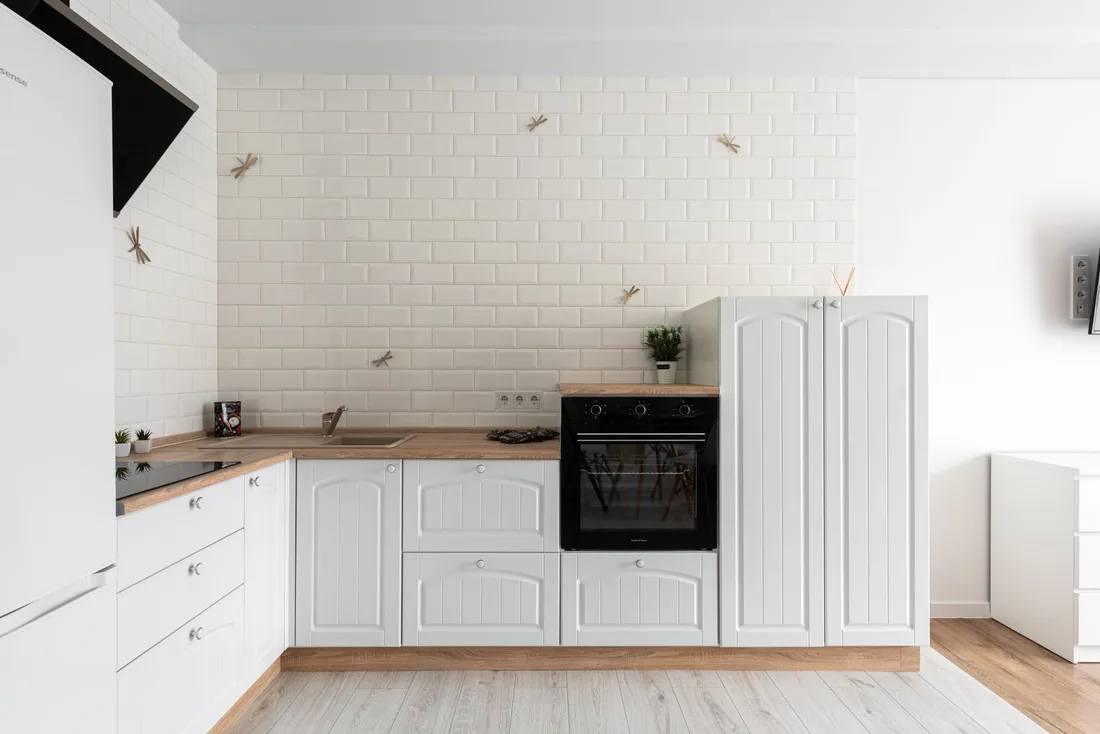 Clean, bright white kitchen with wood countertops and a built-in oven. Photo by Max Vakhtbovych on Pexels