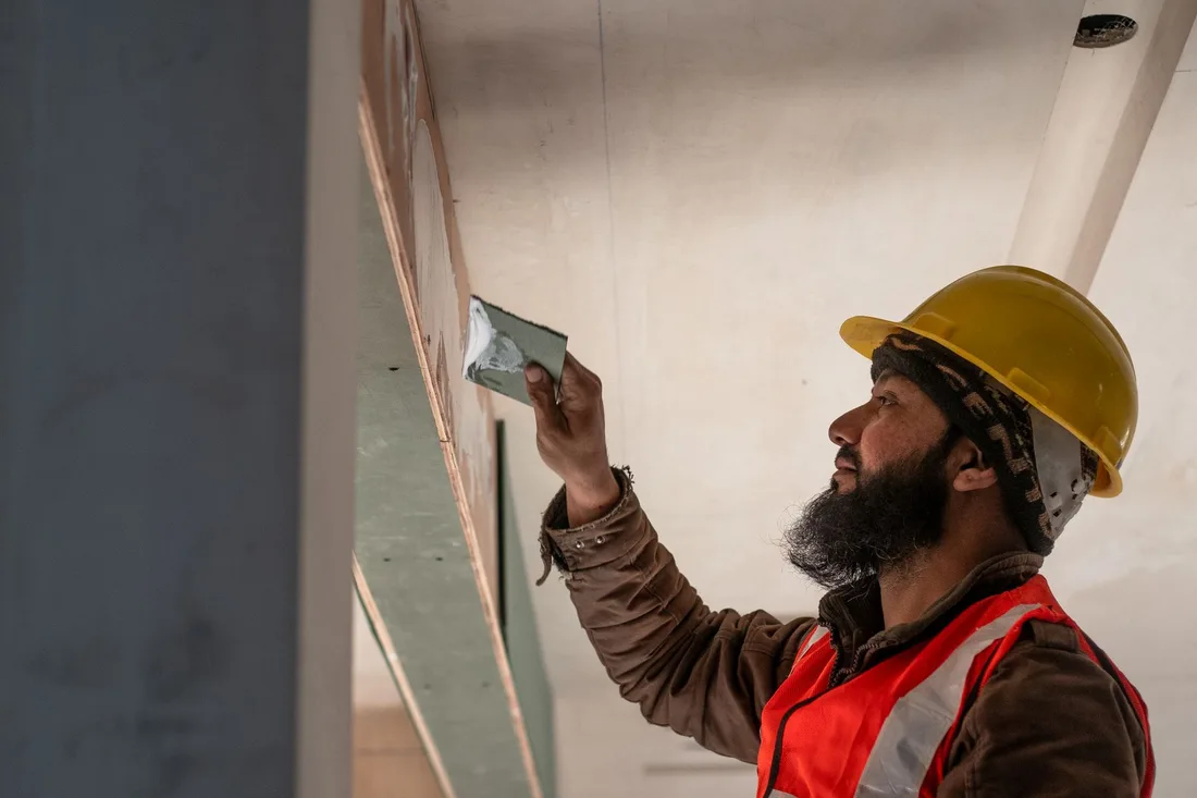 Construction worker in Delhi applies plaster to ceiling, showcasing renovation skills. Photo by Infinity lifespaces on Pexels
