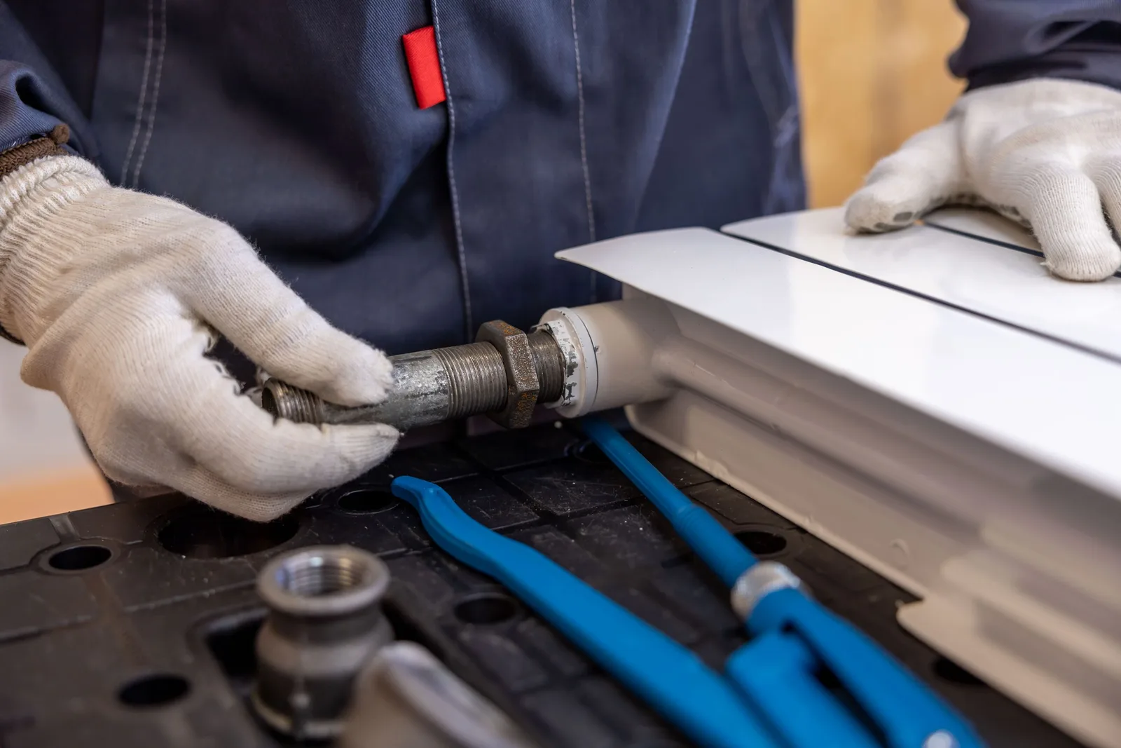 Close-up of a plumber installing a radiator pipe using specialized tools. Photo by Sergei Starostin on Pexels