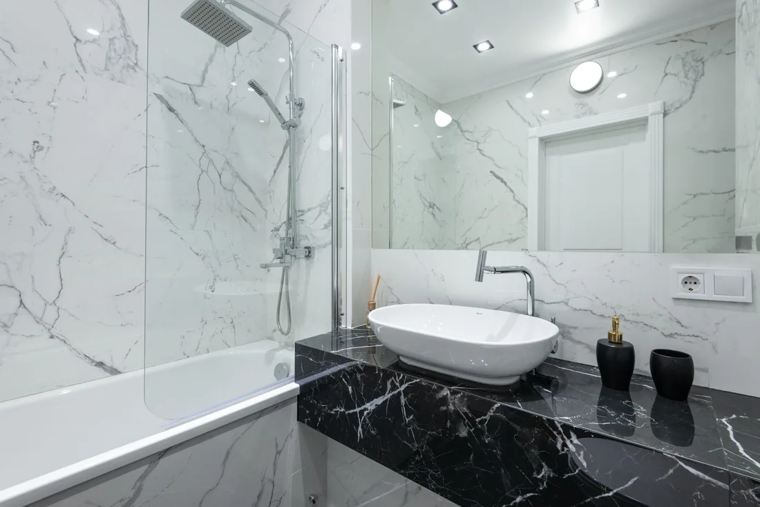 Bright finished bathroom with marble walls, a vessel sink vanity and a glass shower enclosure. Photo by Max Vakhtbovych on Pexels