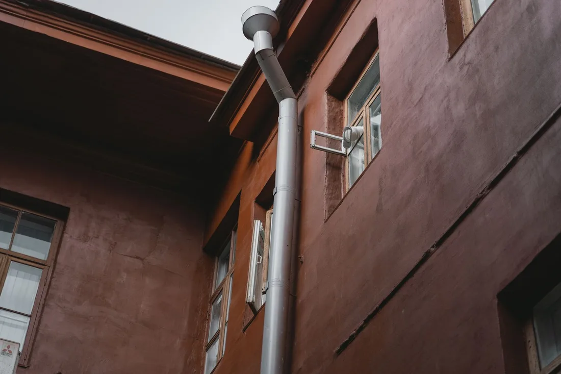 A brown building exterior with pipes and windows, photographed from a low angle. Photo by Tima Miroshnichenko on Pexels
