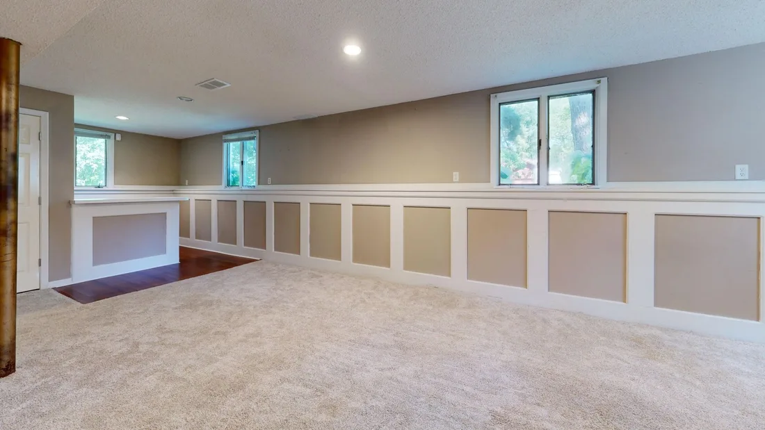 Finished basement room with wainscoting, windows and carpet in a home. Photo by Peter  Vang on Pexels