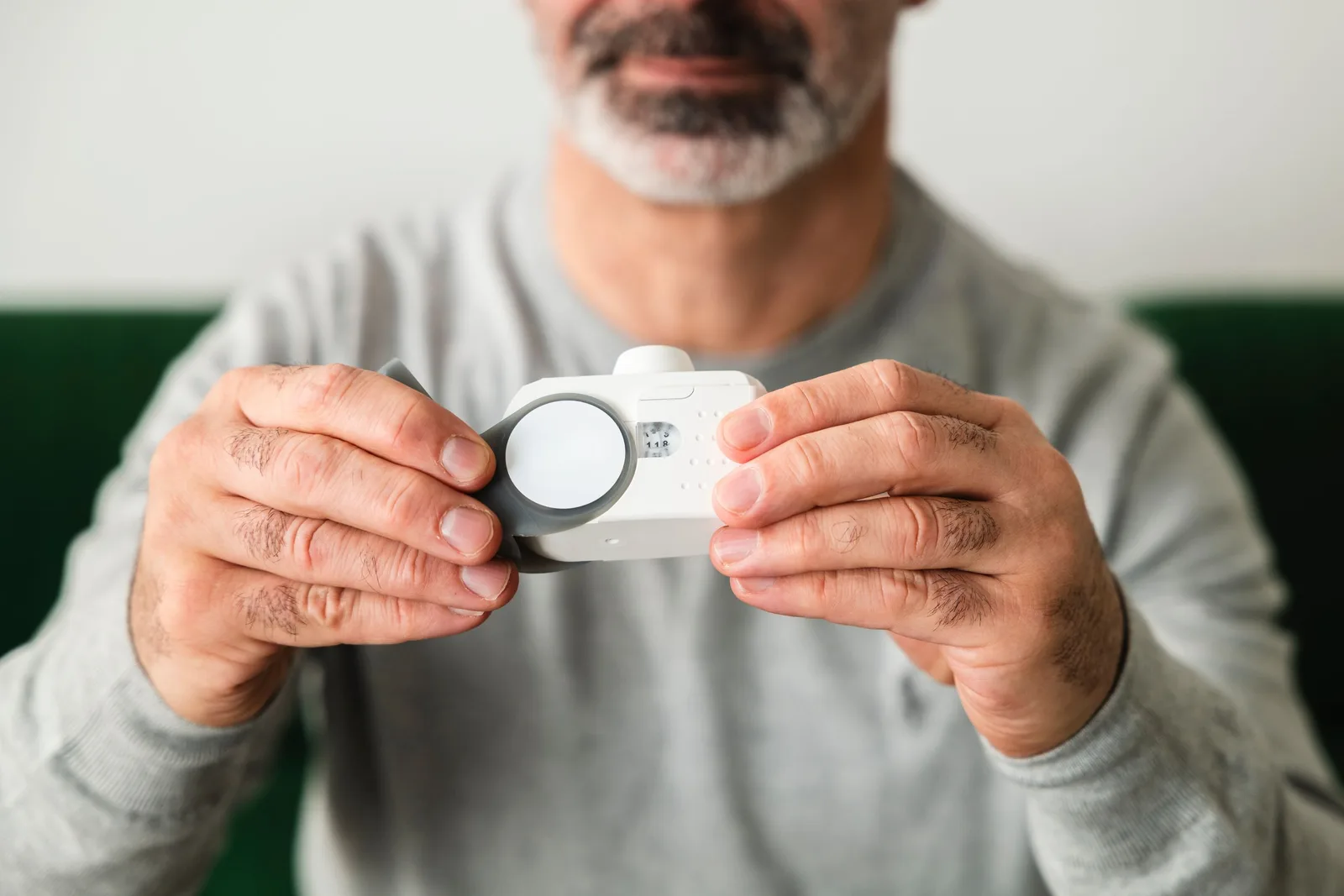Man holding a small round detector to check air quality in a home. Photo by Cnordic Nordic on Pexels