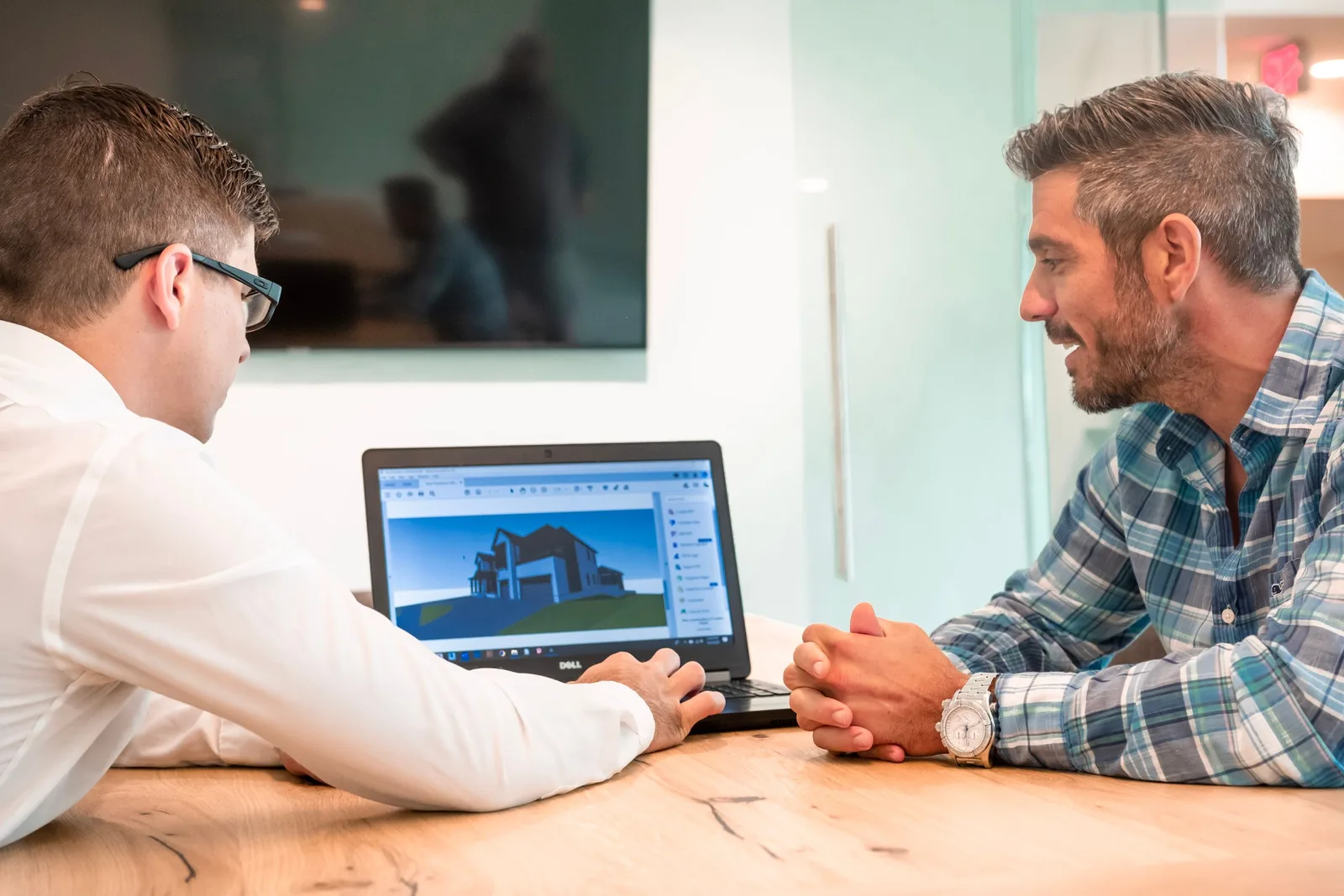 Two professionals discussing a 3D architectural design on a laptop in a modern office. Photo by Grove Brands on Pexels