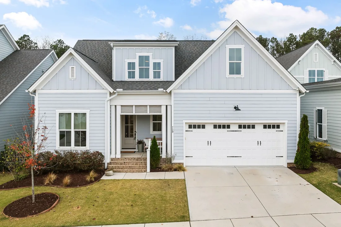 Two-storey white house with a neat roof and two-car garage under a blue sky. Photo by Curtis Adams on Pexels