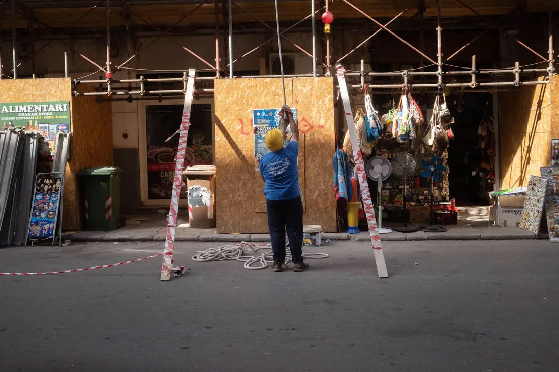 A construction worker standing on a street setting up scaffolding outside an urban storefront. Photo by David Kouakou on Pexels