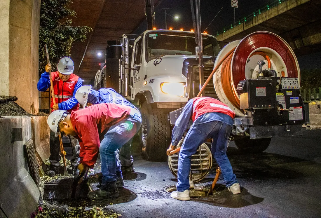 Street workers cleaning drainage at night with machinery under a bridge. Photo by JESUS ADRIÁN SAAVEDRA on Pexels