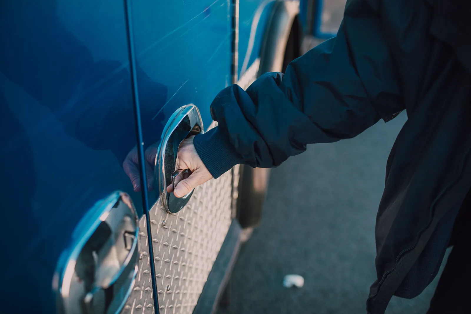 A person in a jacket opens a handle on a blue emergency vehicle, likely an ambulance. Photo by RDNE Stock project on Pexels