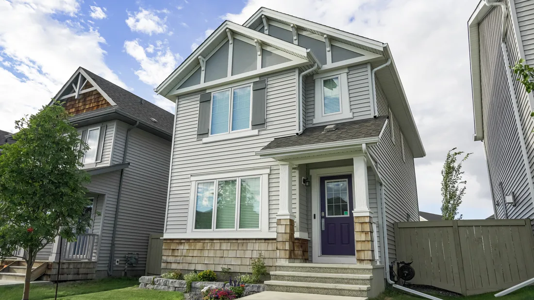 Two-story house with gray siding, stone base and landscaped front yard. Photo by Jared VanderMeer on Pexels