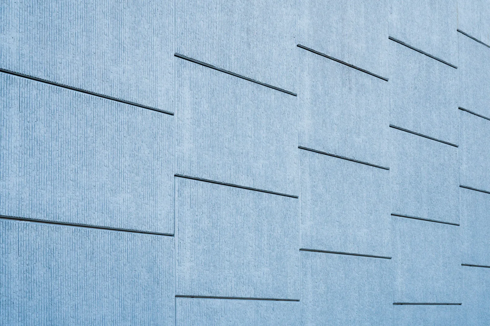 Blue tinted concrete wall featuring sleek geometric lines and modern architecture. Photo by Brett Sayles on Pexels