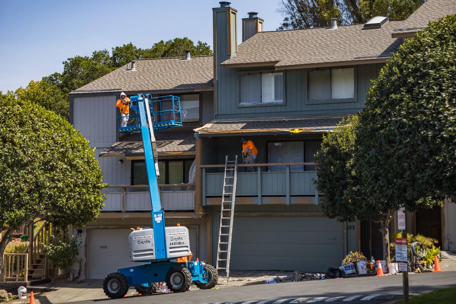 Worker on an aerial lift next to a two-story townhouse exterior. Photo by Robert So on Pexels