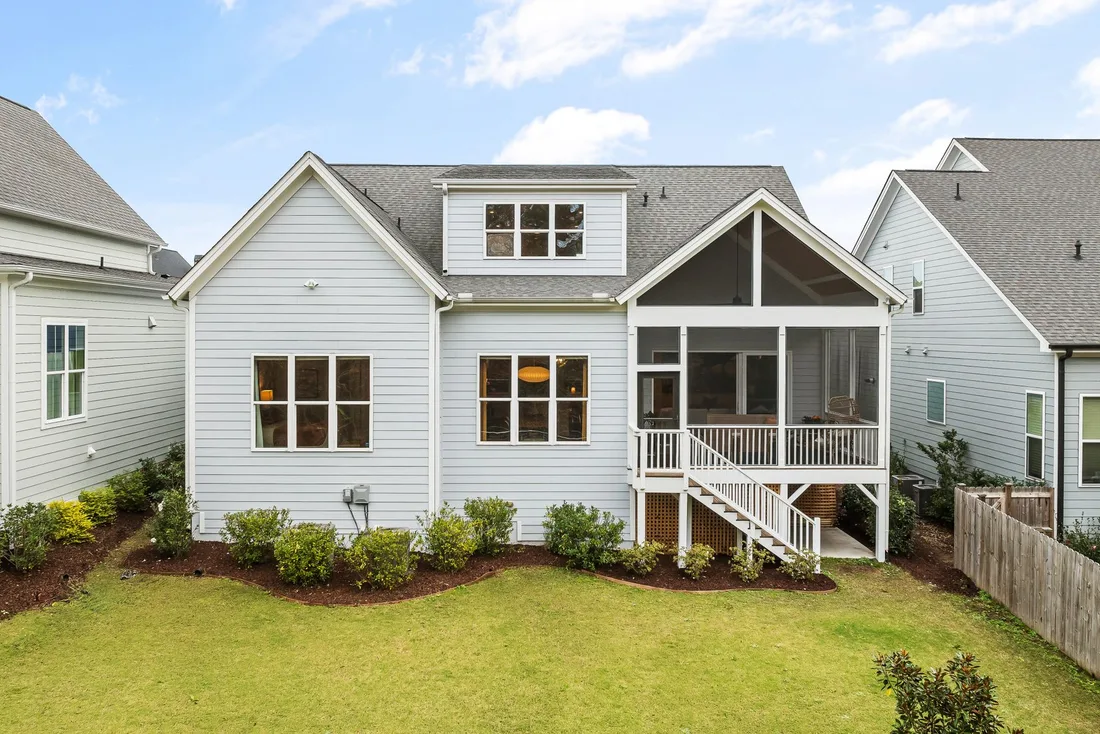 White two-story house with fresh siding, screened porch and neat lawn. Photo by Curtis Adams on Pexels