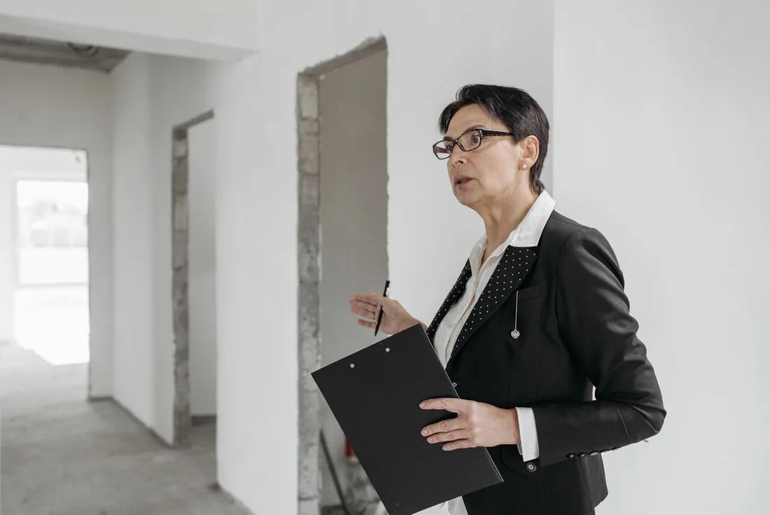 Woman in a suit holding a clipboard, inspecting an unfinished indoor construction site. Photo by Pavel Danilyuk on Pexels