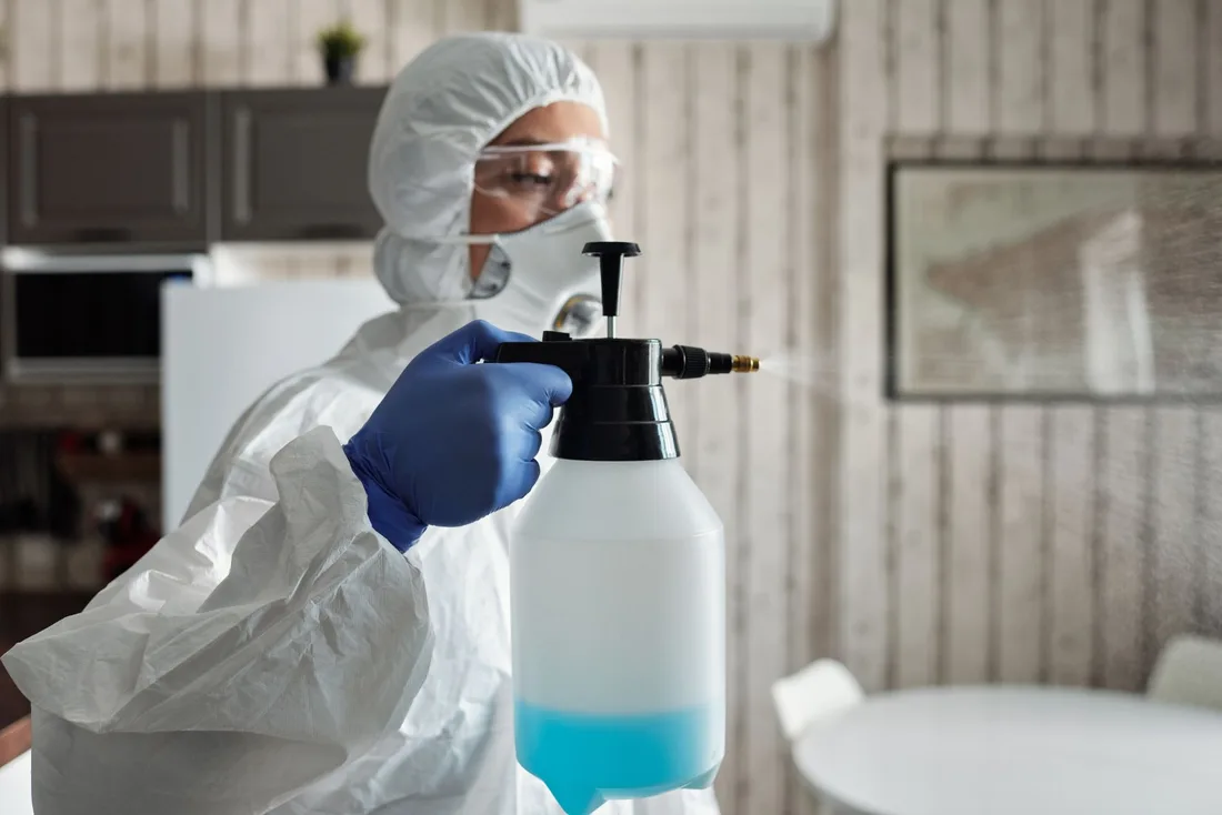 Pest control technician in protective suit spraying treatment inside a home in Australia. Photo by Matilda Wormwood on Pexels