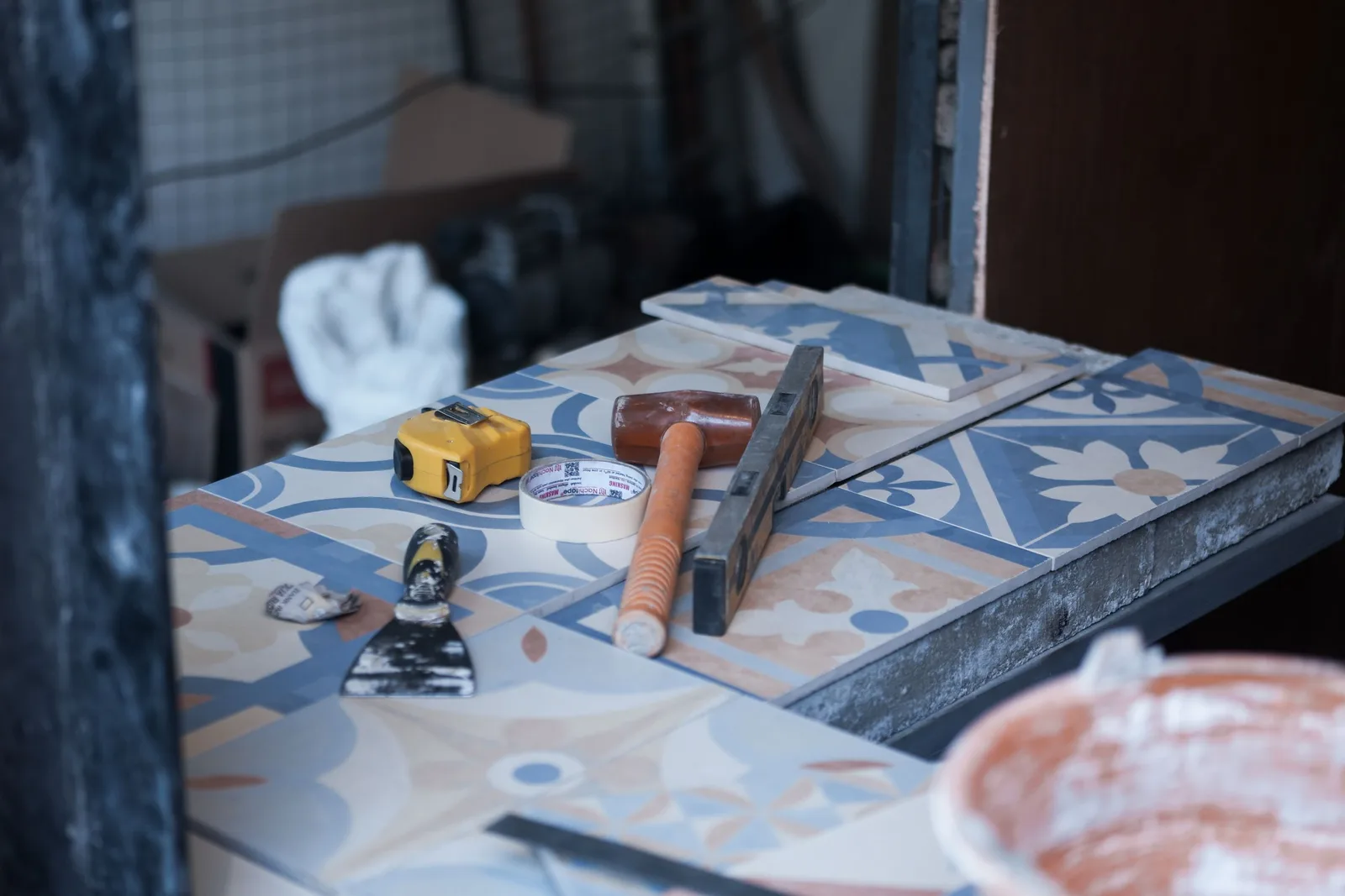 Patterned floor tiles being laid with a level, trowel and tools on a worksite. Photo by Bimbim Sindu on Pexels