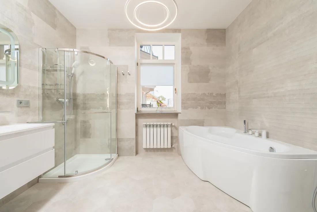Bright finished bathroom with light tiled walls, a glass shower and a freestanding bath. Photo by Max Vakhtbovych on Pexels