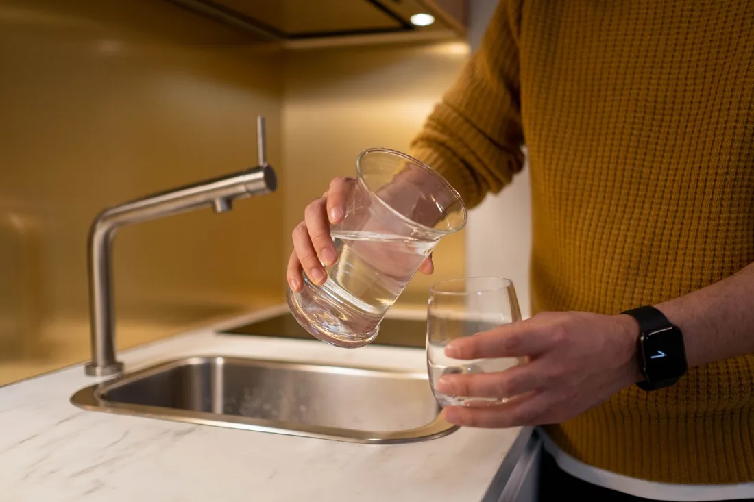 Person filling a glass of water at a modern kitchen sink. Photo by cottonbro studio on Pexels