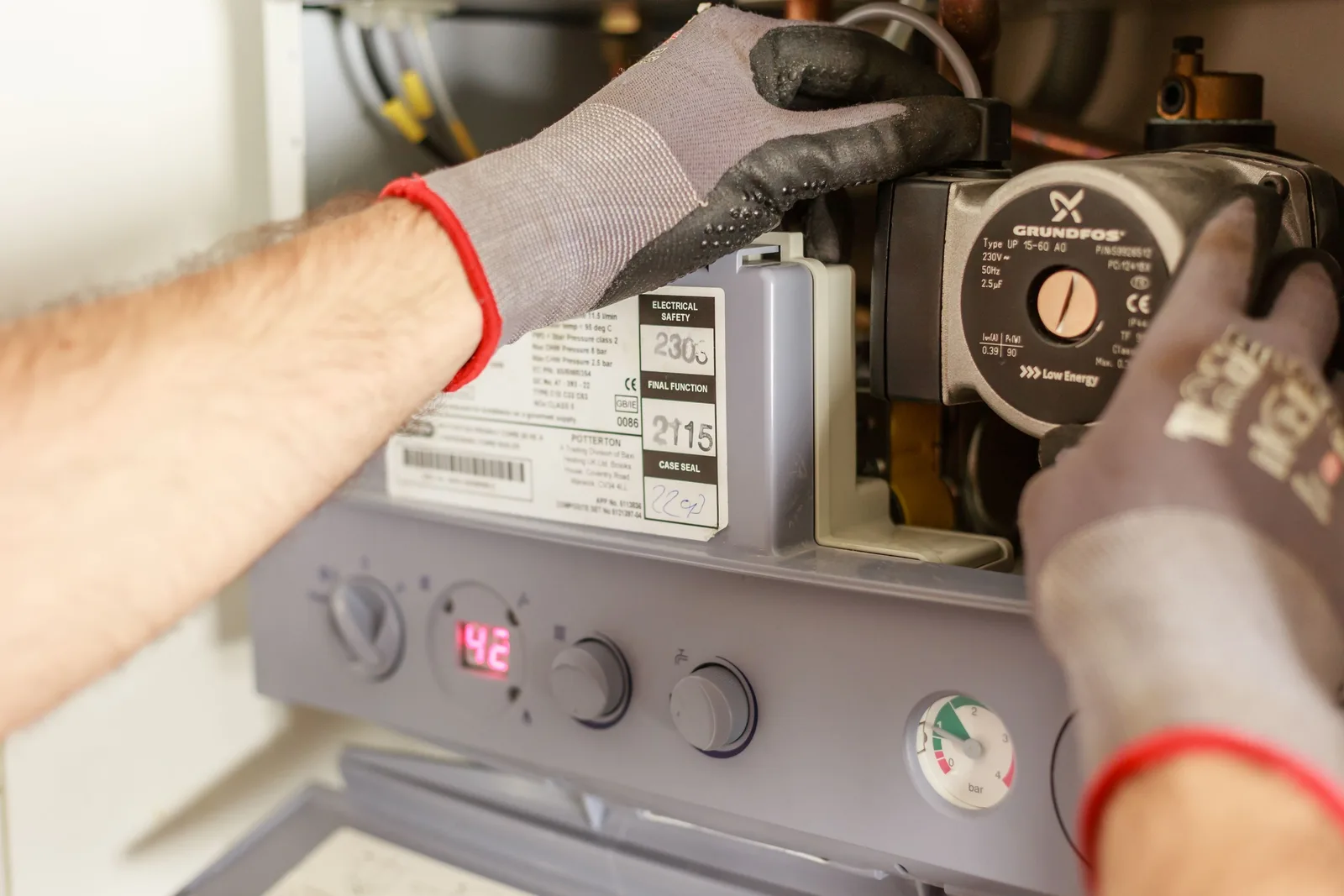Close-up of hands adjusting a boiler system with precise instrumentation, showing maintenance work. Photo by Heiko Ruth on Pexels