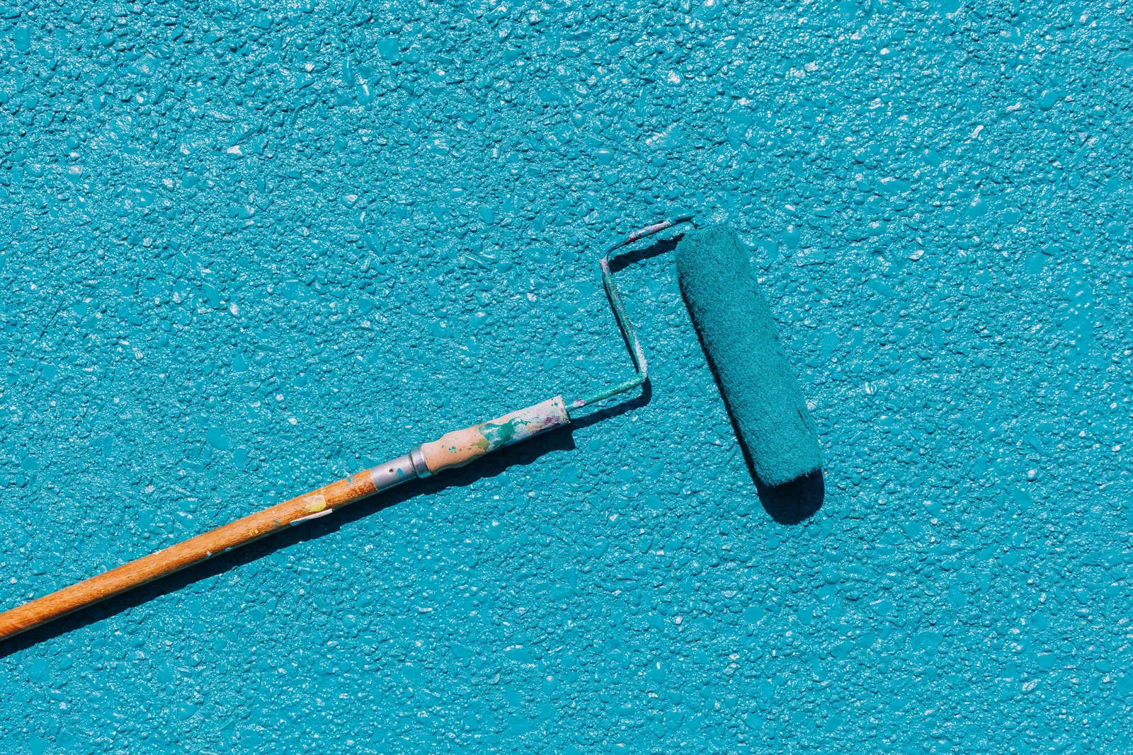 Roller applying blue waterproof coating to a surface. Photo by K on Pexels