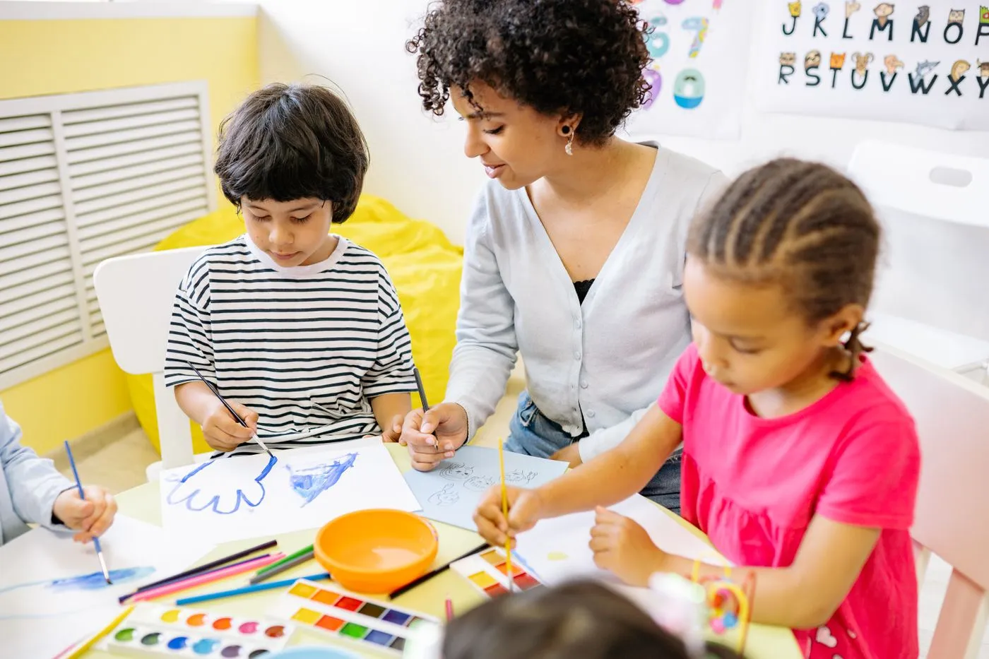 Childcare teacher with a group of children in a bright room. Photo by Yan Krukau on Pexels