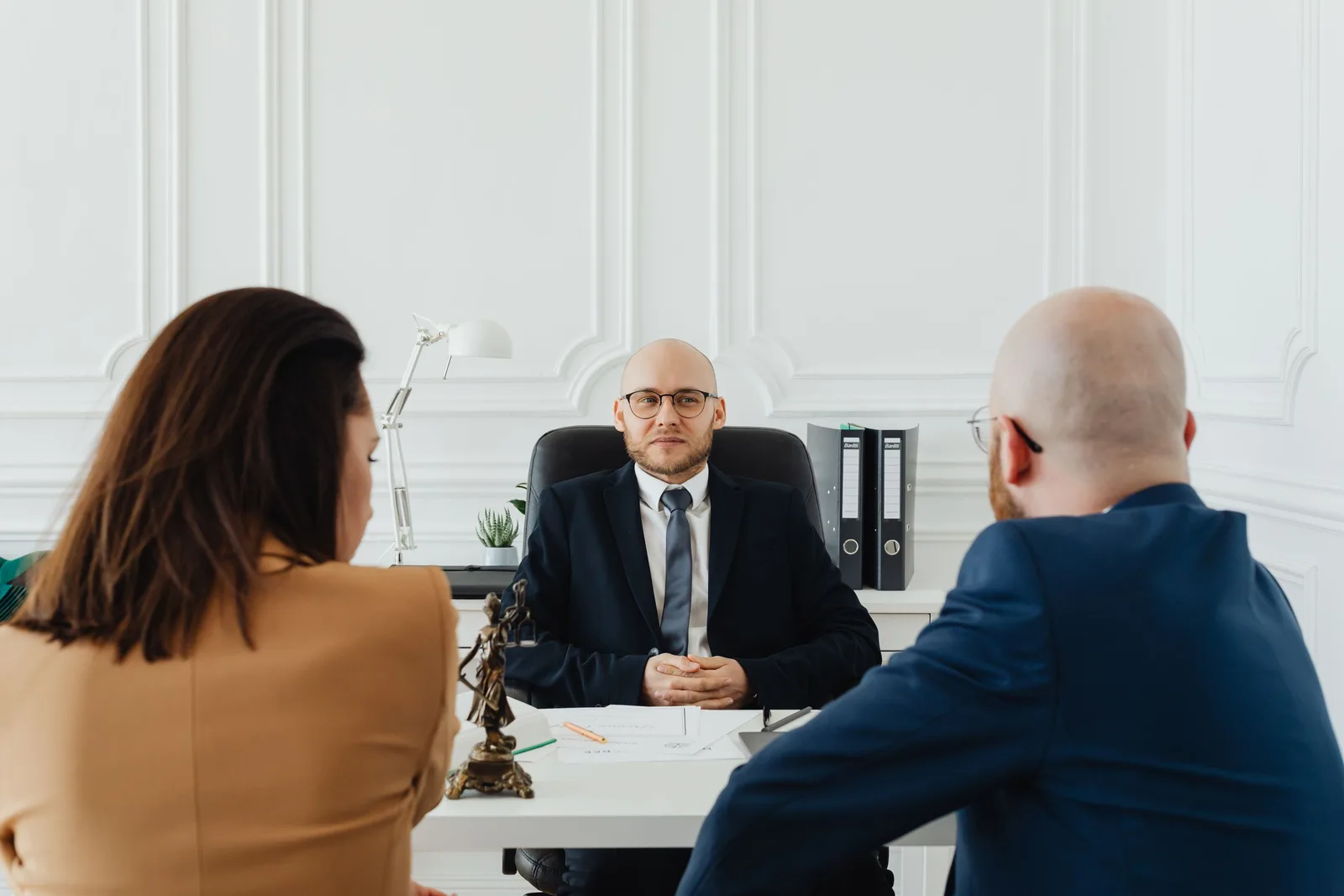 Family lawyer seated at a bright white desk meeting with clients. Photo by https://kaboompics.com/ on Pexels