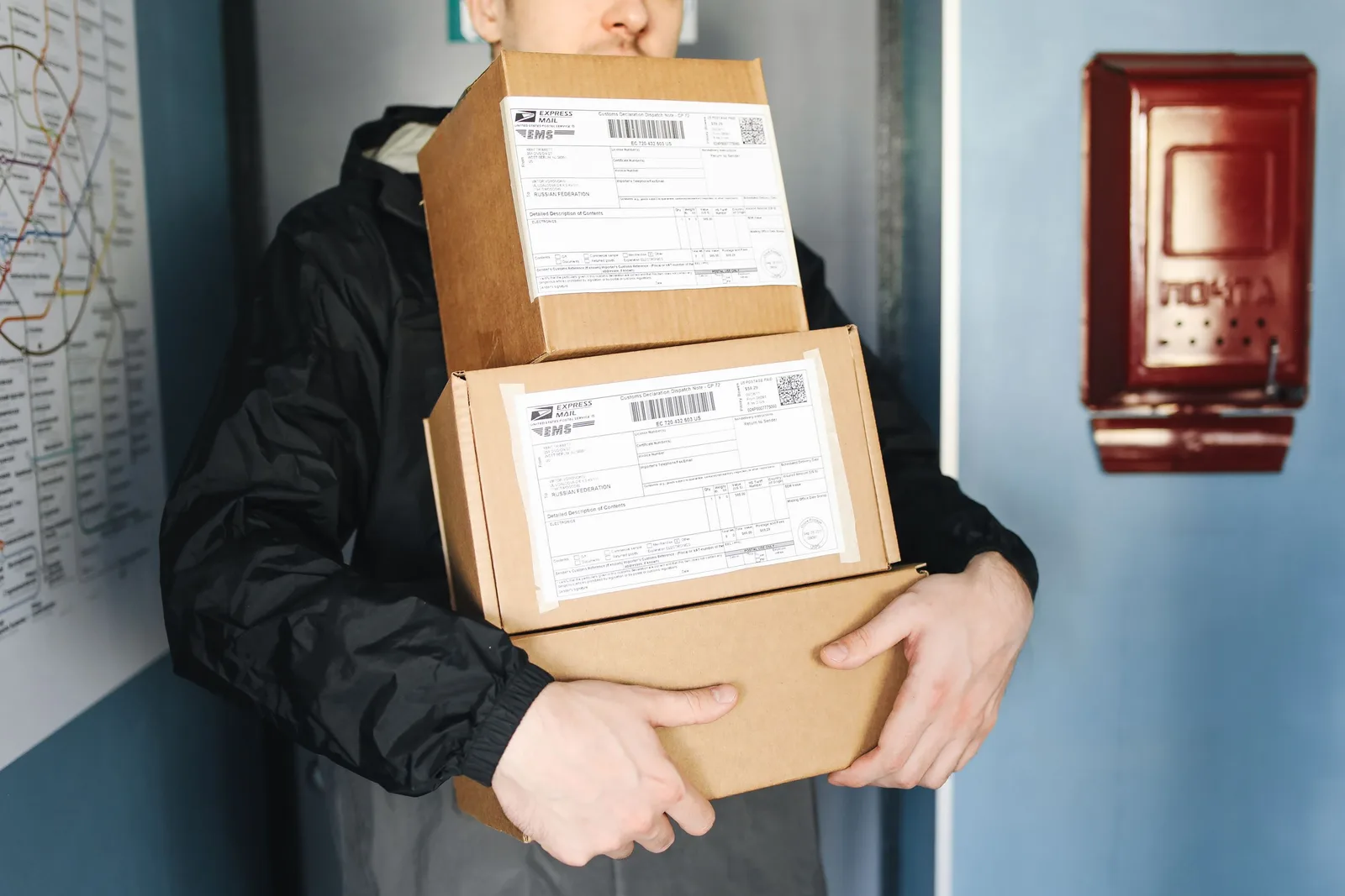 Courier carrying stacked cardboard packages for delivery service indoors.. Photo by Polina Tankilevitch on Pexels