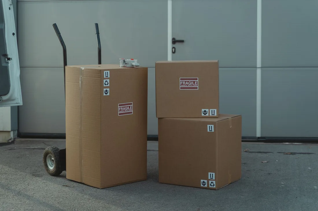 Three cardboard boxes on a dolly, ready for shipping outside a warehouse.. Photo by Tima Miroshnichenko on Pexels