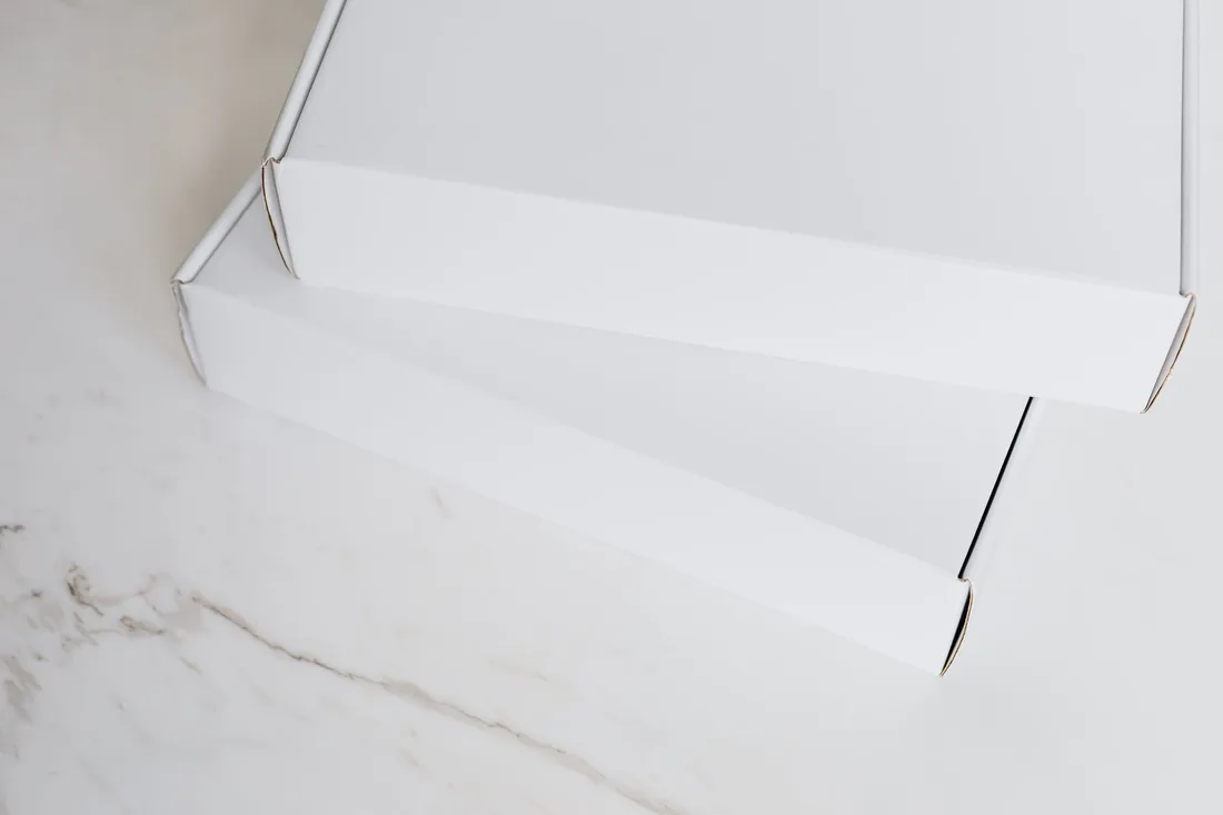 Open white mailer box on a white marble surface. Photo by https://kaboompics.com/ on Pexels