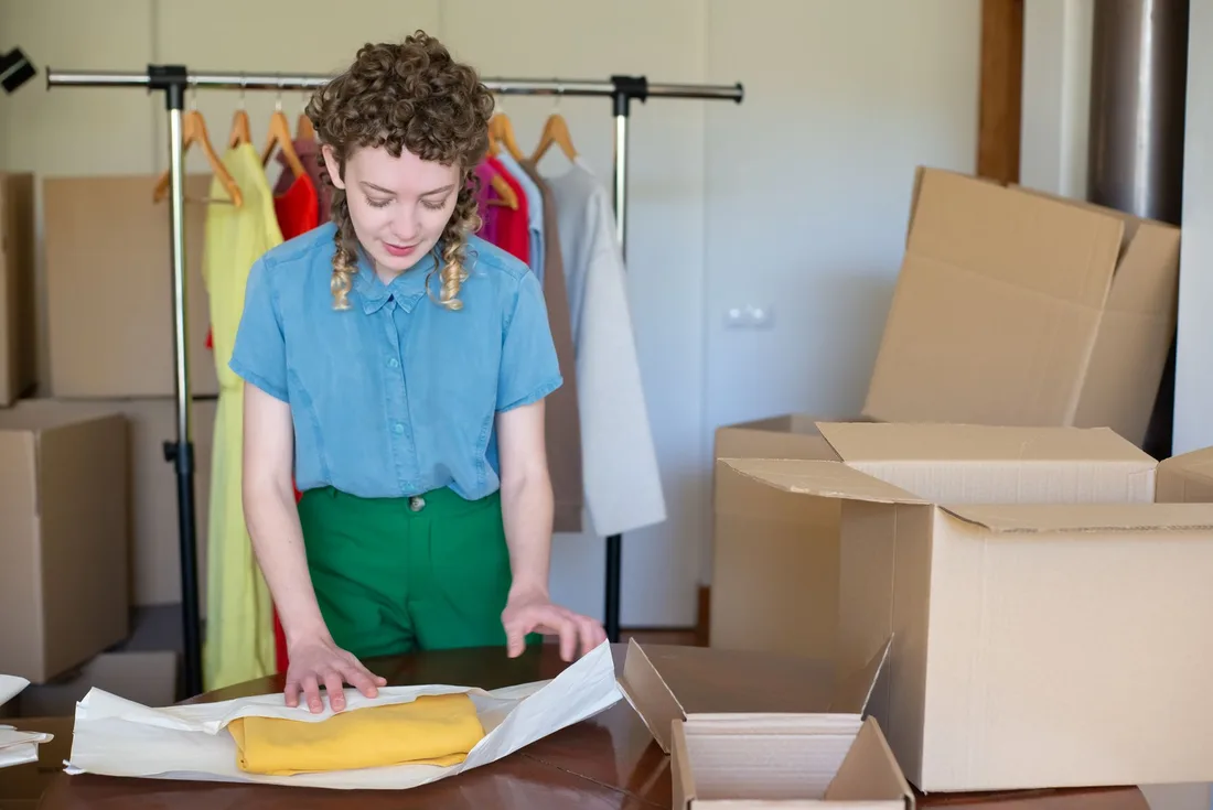 A young female entrepreneur packaging clothes in eco-friendly boxes in her online store workspace.. Photo by Kampus Production on Pexels