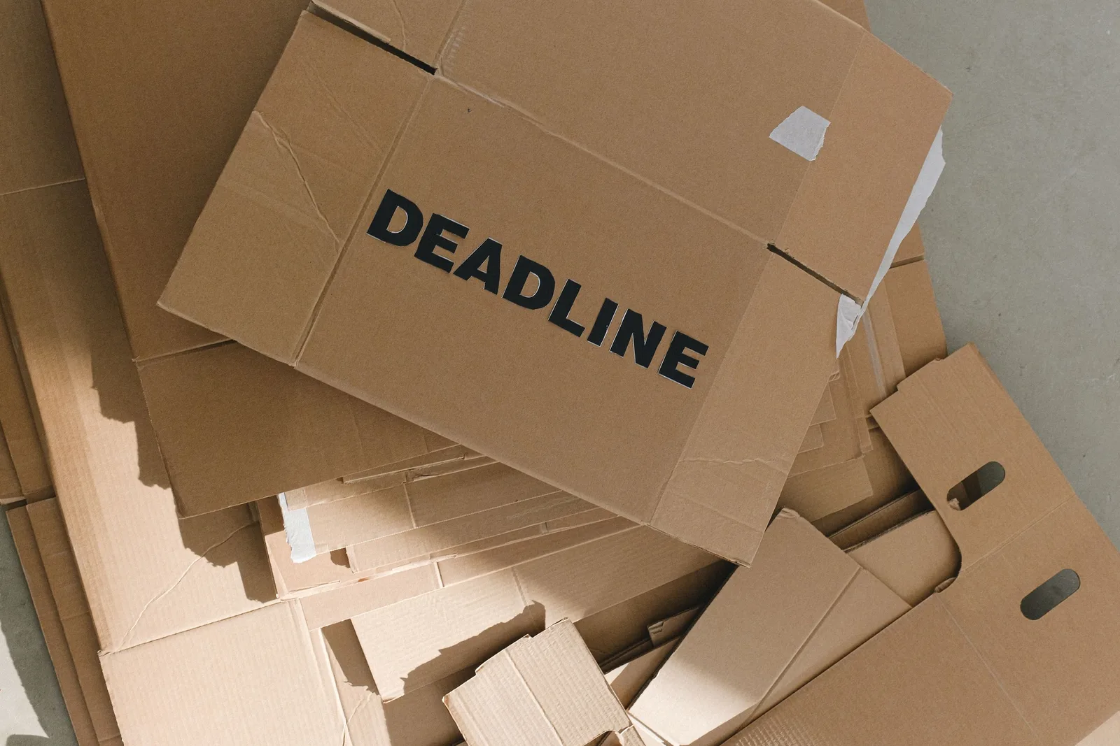Pile of cardboard boxes with bold 'Deadline' label indoors, emphasizing urgency.. Photo by SHVETS production on Pexels