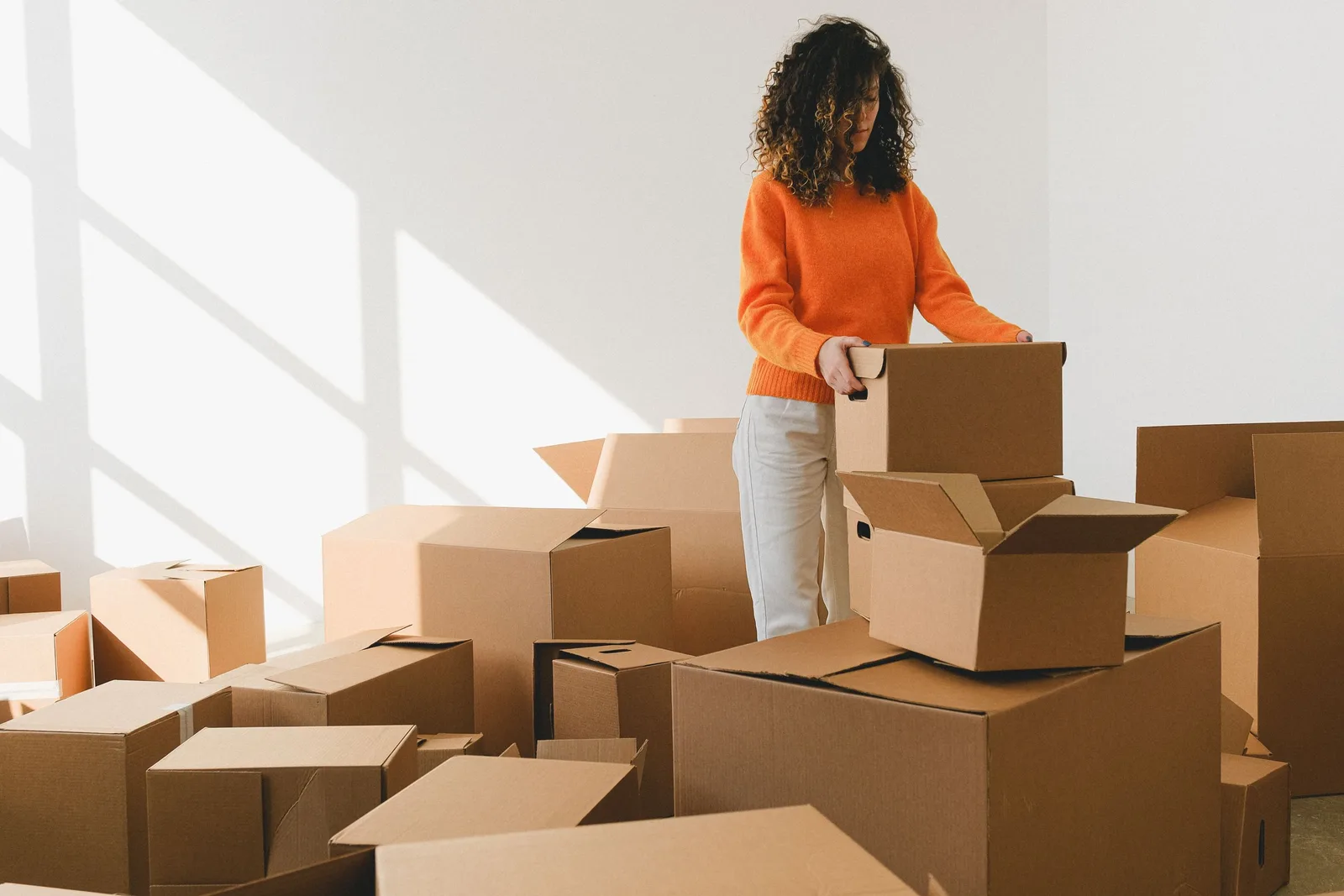 Woman packing and sorting cardboard shipping boxes. Photo by SHVETS production on Pexels