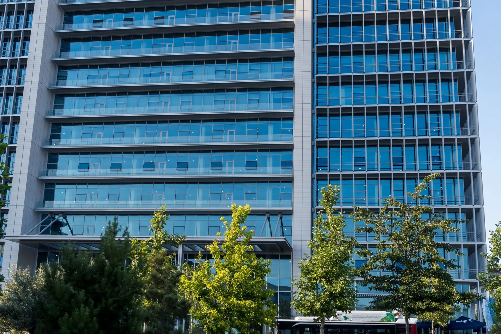 Modern blue glass office tower surrounded by trees on a clear day. Photo by Zulfugar Karimov on Pexels