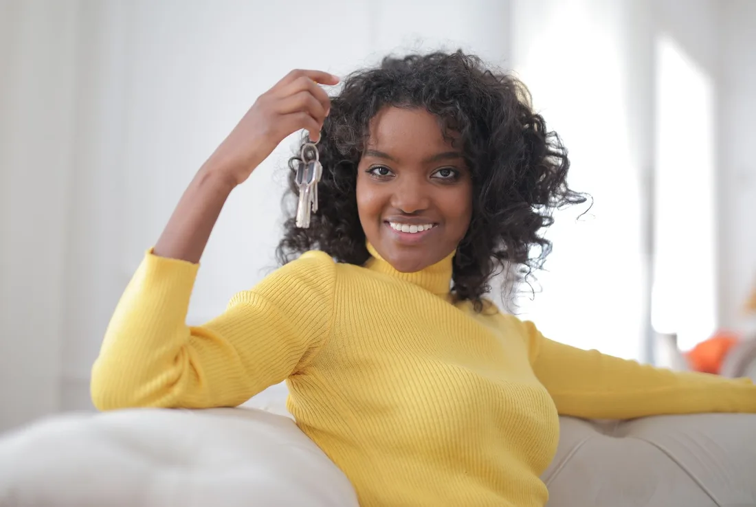 Smiling woman relaxing on a white sofa in her new apartment. Photo by Andrea Piacquadio on Pexels