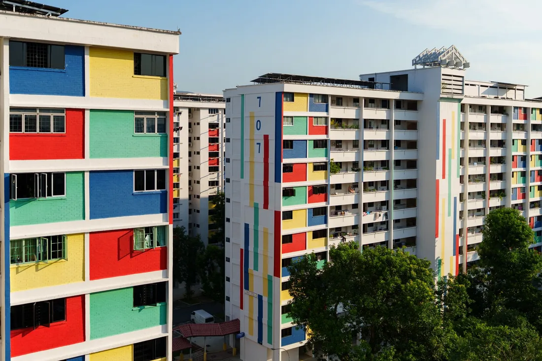 Colorful high-rise public housing blocks surrounded by trees. Photo by Richard L on Pexels