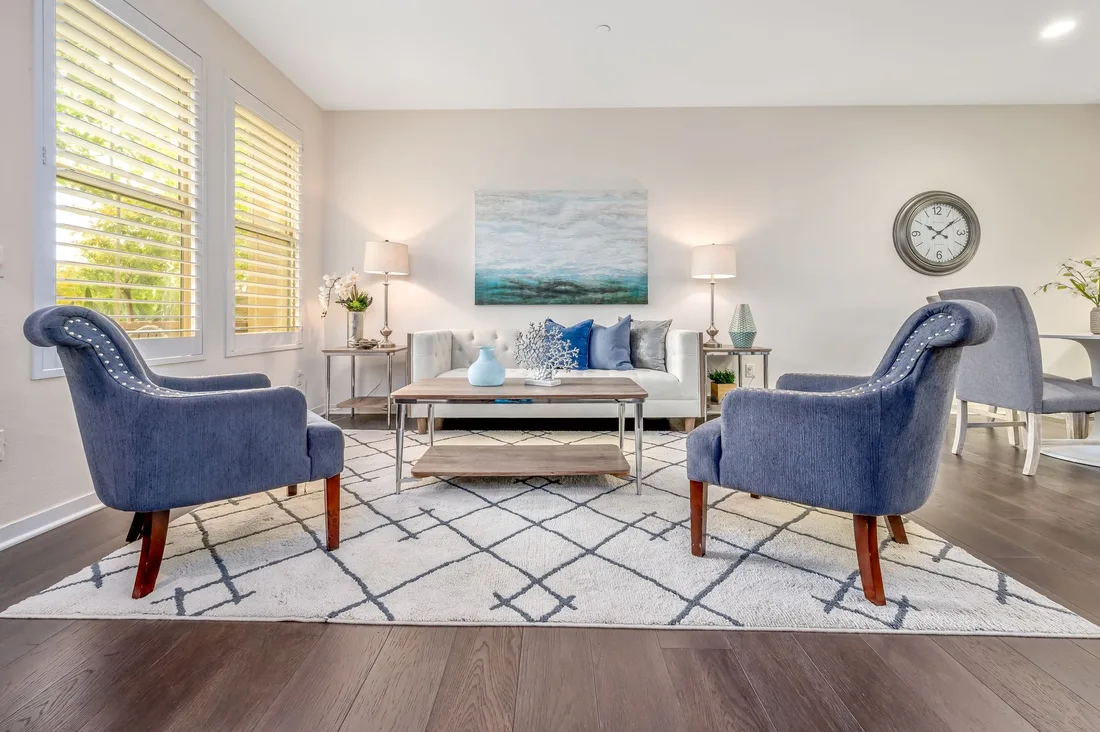 Beautifully staged living room with blue armchairs, patterned rug and soft natural light. Photo by Terry Magallanes on Pexels