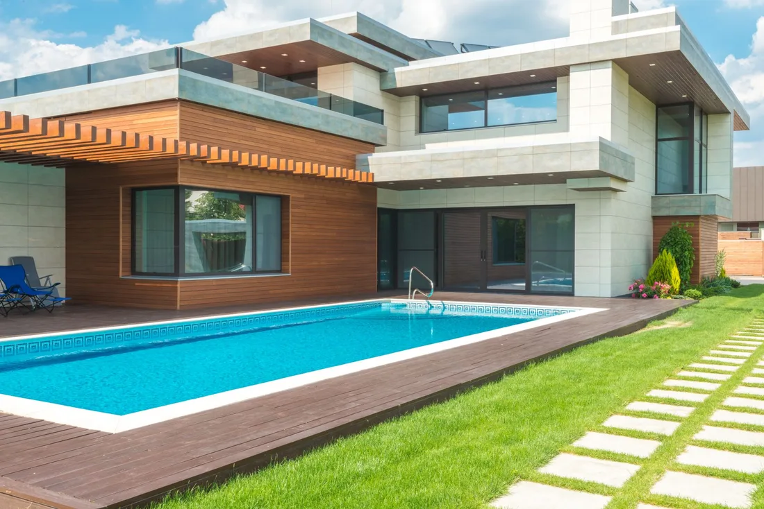Modern luxury house with a swimming pool, timber deck and manicured lawn. Photo by Max Vakhtbovych on Pexels