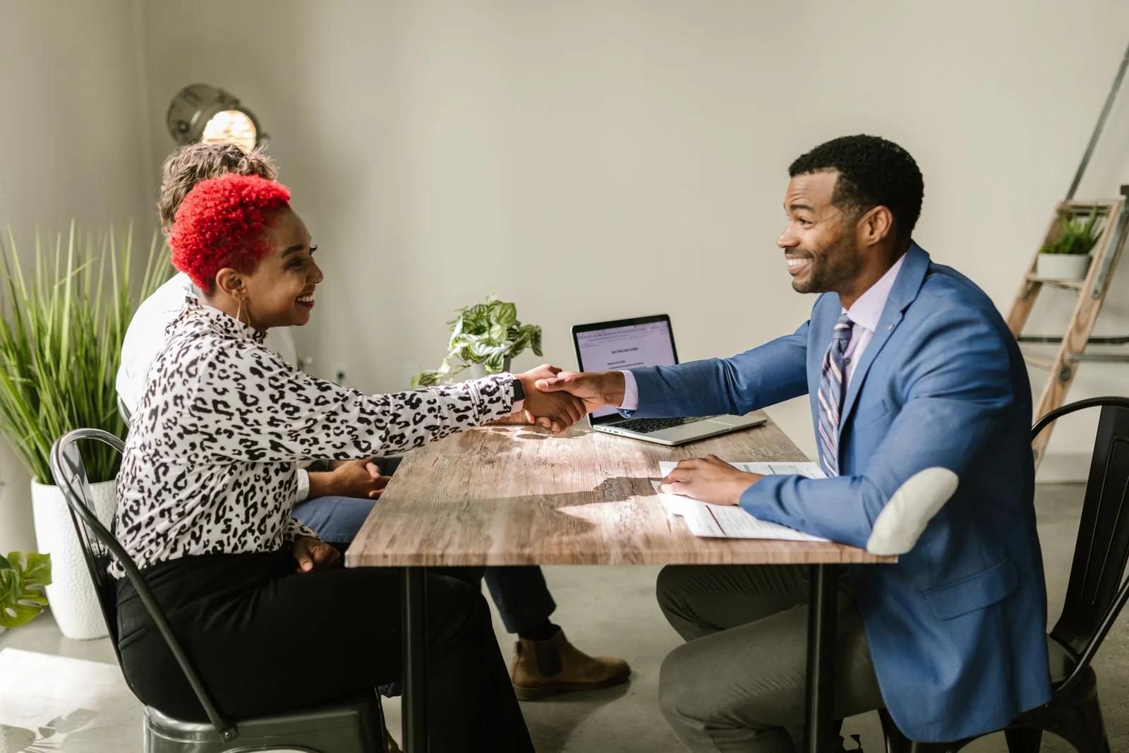 Mortgage broker shaking hands with a client across a table with a laptop. Photo by RDNE Stock project on Pexels