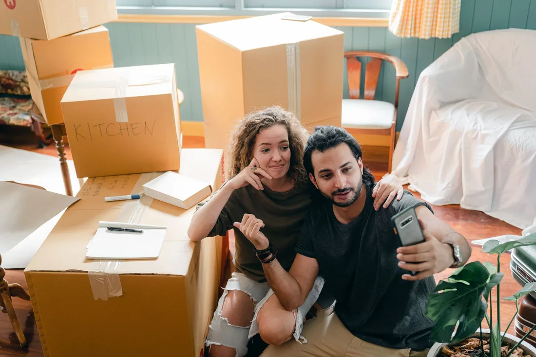 Couple sitting on the floor of their new home among moving boxes. Photo by Ketut Subiyanto on Pexels