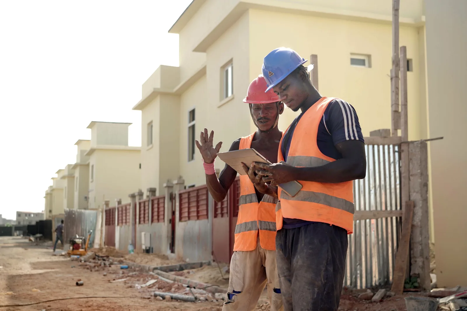Two developers in high-visibility vests reviewing plans on a tablet at a housing construction site. Photo by José Carlos Alexandre on Pexels