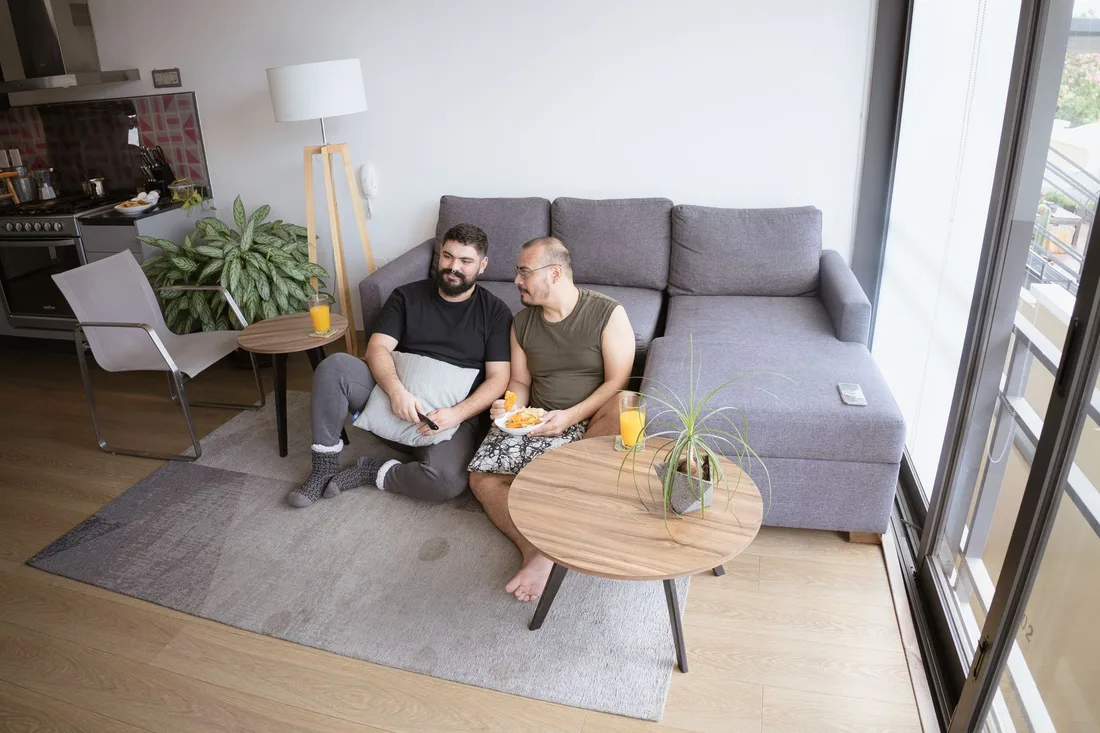 Two tenants relaxing on a grey sofa with a laptop in a bright apartment living room. Photo by Los Muertos Crew on Pexels