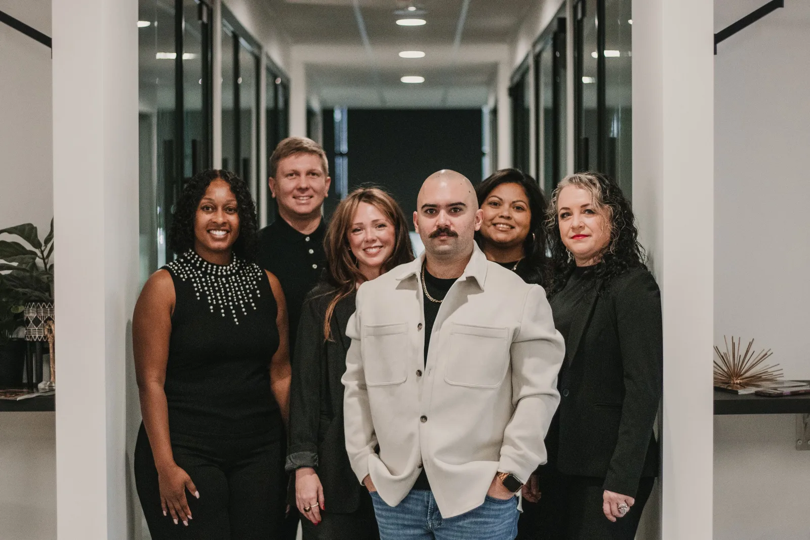 Property management team of smiling professionals standing together in a bright office corridor. Photo by Daniel & Hannah Snipes on Pexels