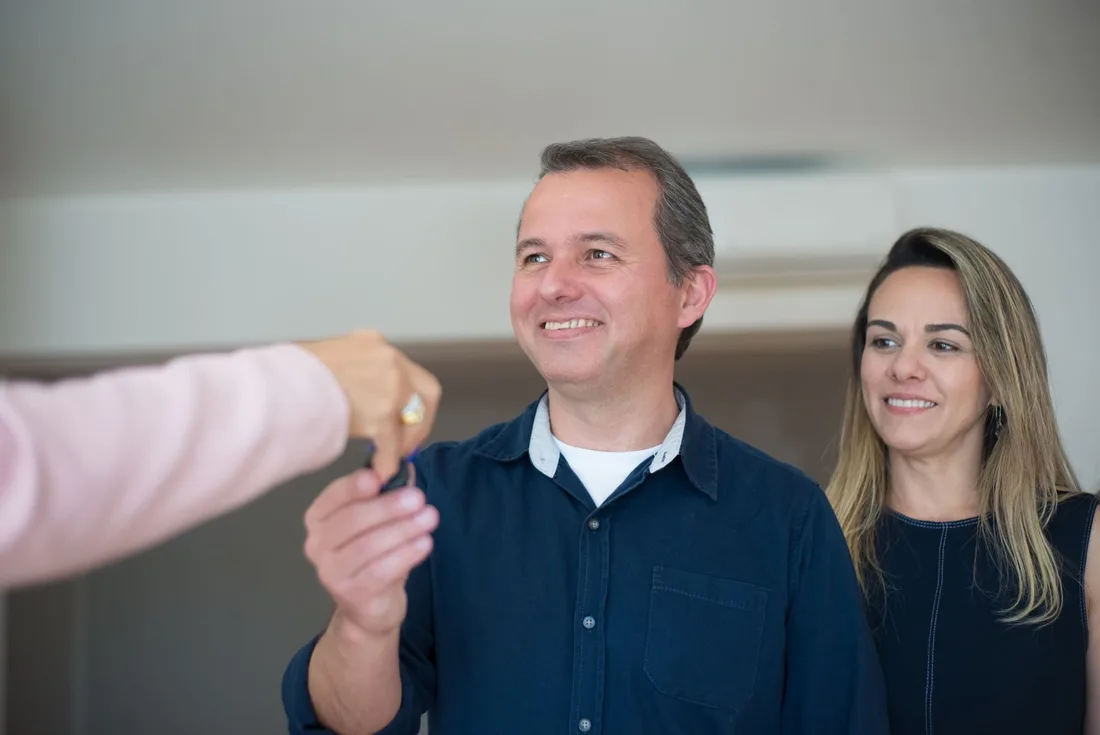 Smiling couple receiving house keys from an agent in their new home. Photo by Kampus Production on Pexels