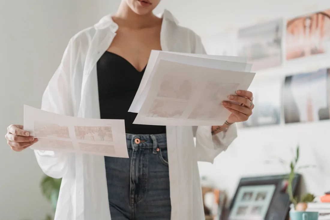 Real estate agent in white shirt reviewing printed listing photos in a bright room. Photo by George Milton on Pexels