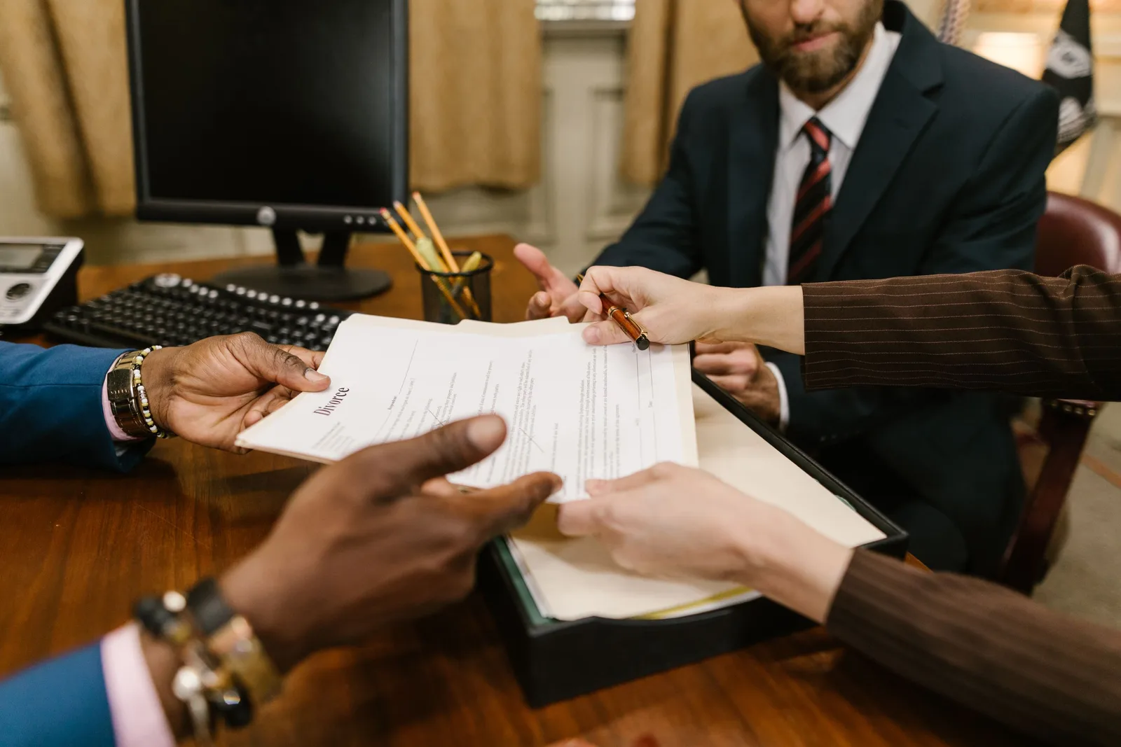 Escrow officer passing signed closing documents across a desk to a client. Photo by RDNE Stock project on Pexels