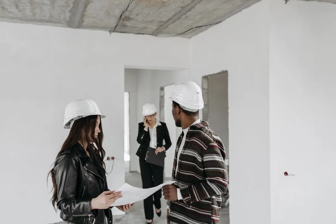 Homeowner and contractor in hard hats reviewing plans in a bright empty room. Photo by Pavel Danilyuk on Pexels