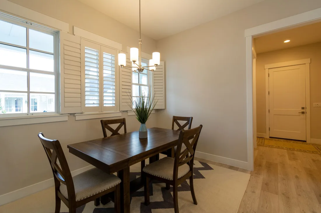 Finished dining room with wooden table, chandelier and white plantation shutters. Photo by Get Lost Mike on Pexels