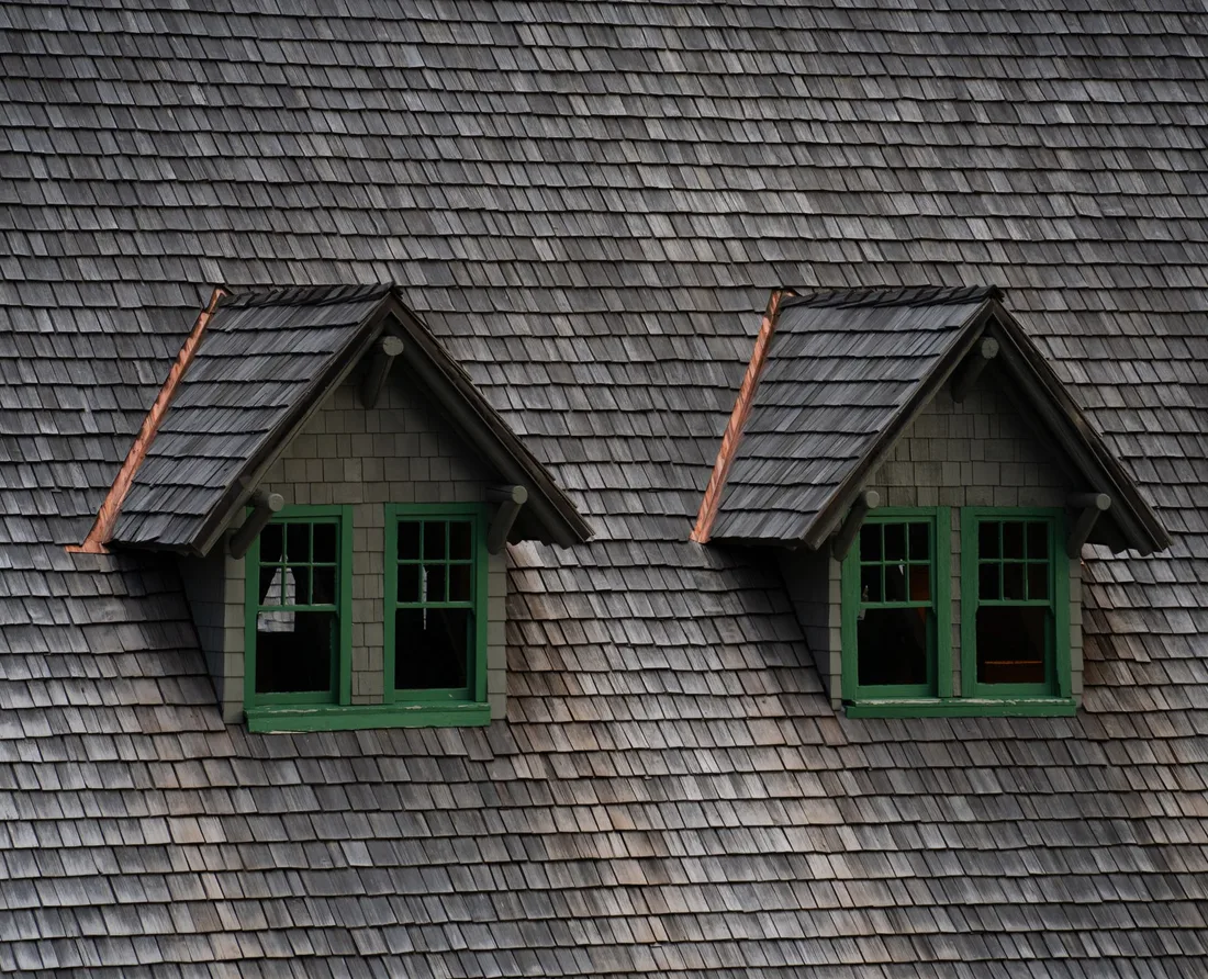 Newly shingled roof with two green-framed dormer windows on a clean roof. Photo by Alex Moliski on Pexels
